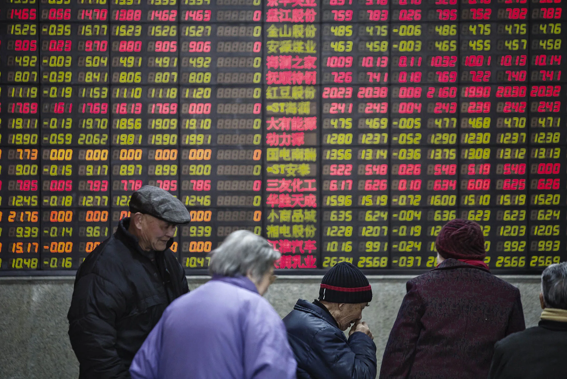 People stand in front of an electronic board displaying share prices at a securities exchange house in Shanghai, China, on Monday, Feb. 15, 2015. China's stocks fell as trading resumed after a week-long holiday which saw global equities enter a bear market on concern over the strength of the world economy.
