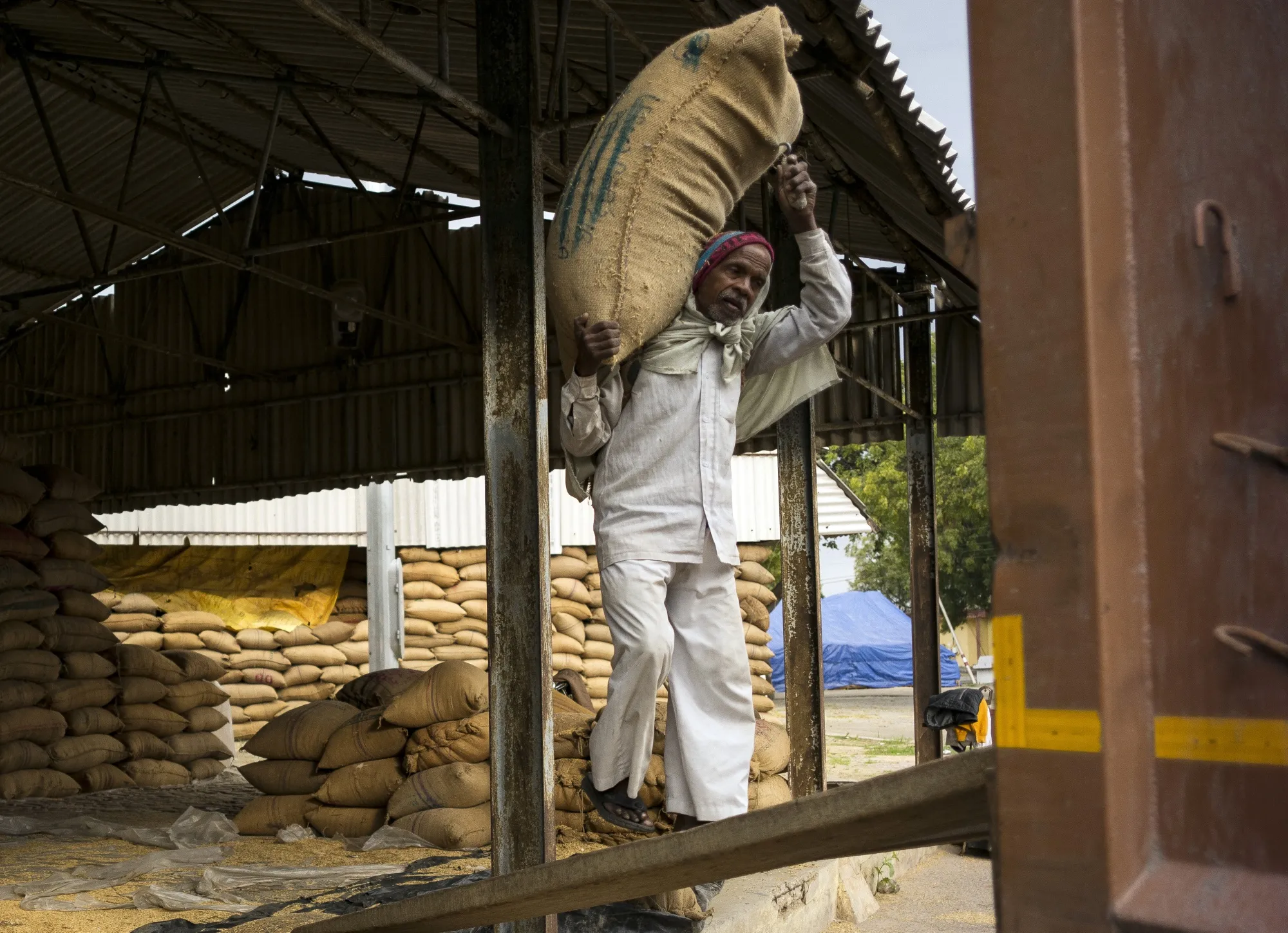 A worker carries a sack of rice at a wholesale grain market in Dankaur, Uttar Pradesh, India.&nbsp;