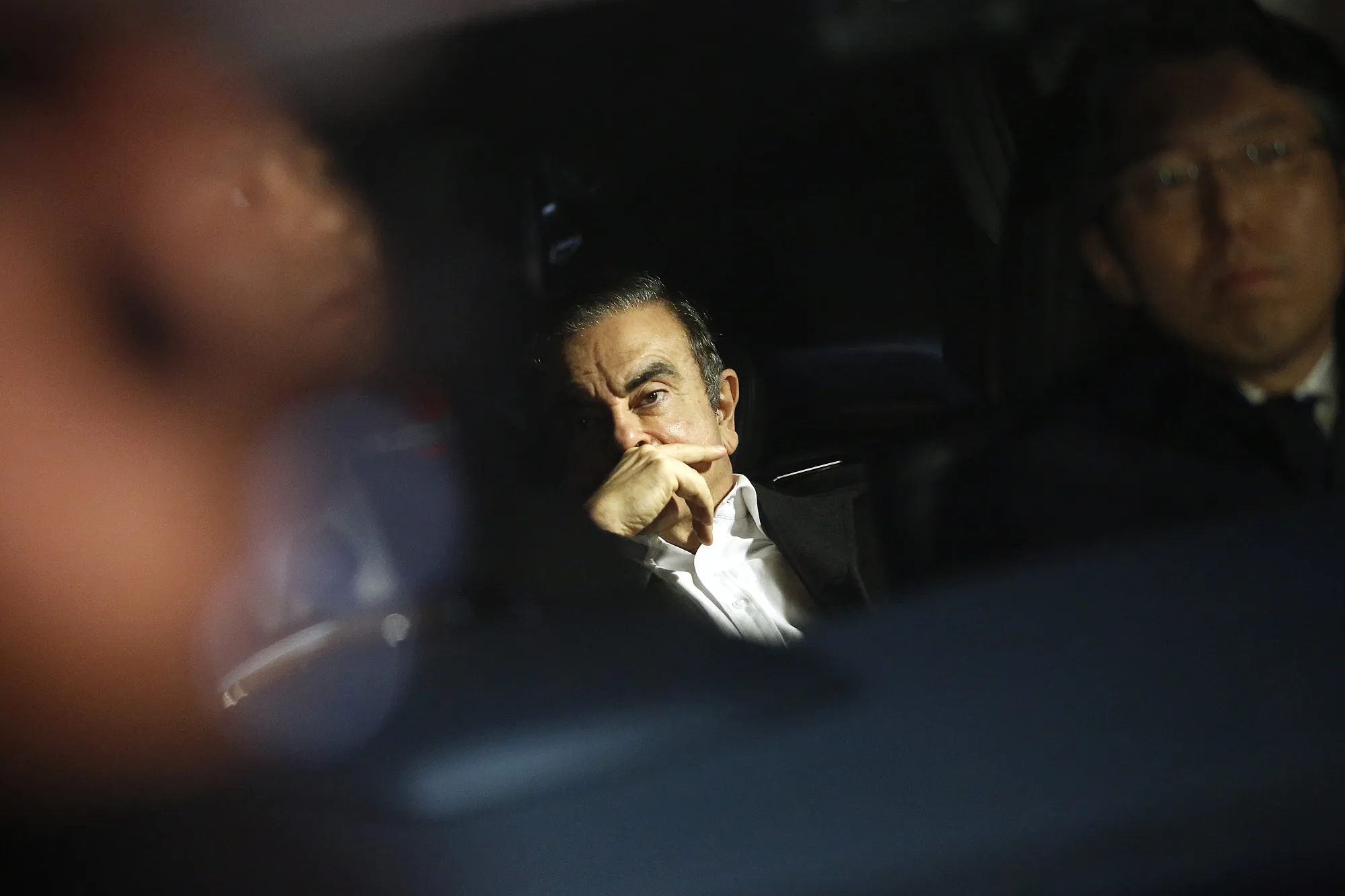 Carlos Ghosn, center, sits in a vehicle as he leaves his lawyer's office in Tokyo on&nbsp;March 6.