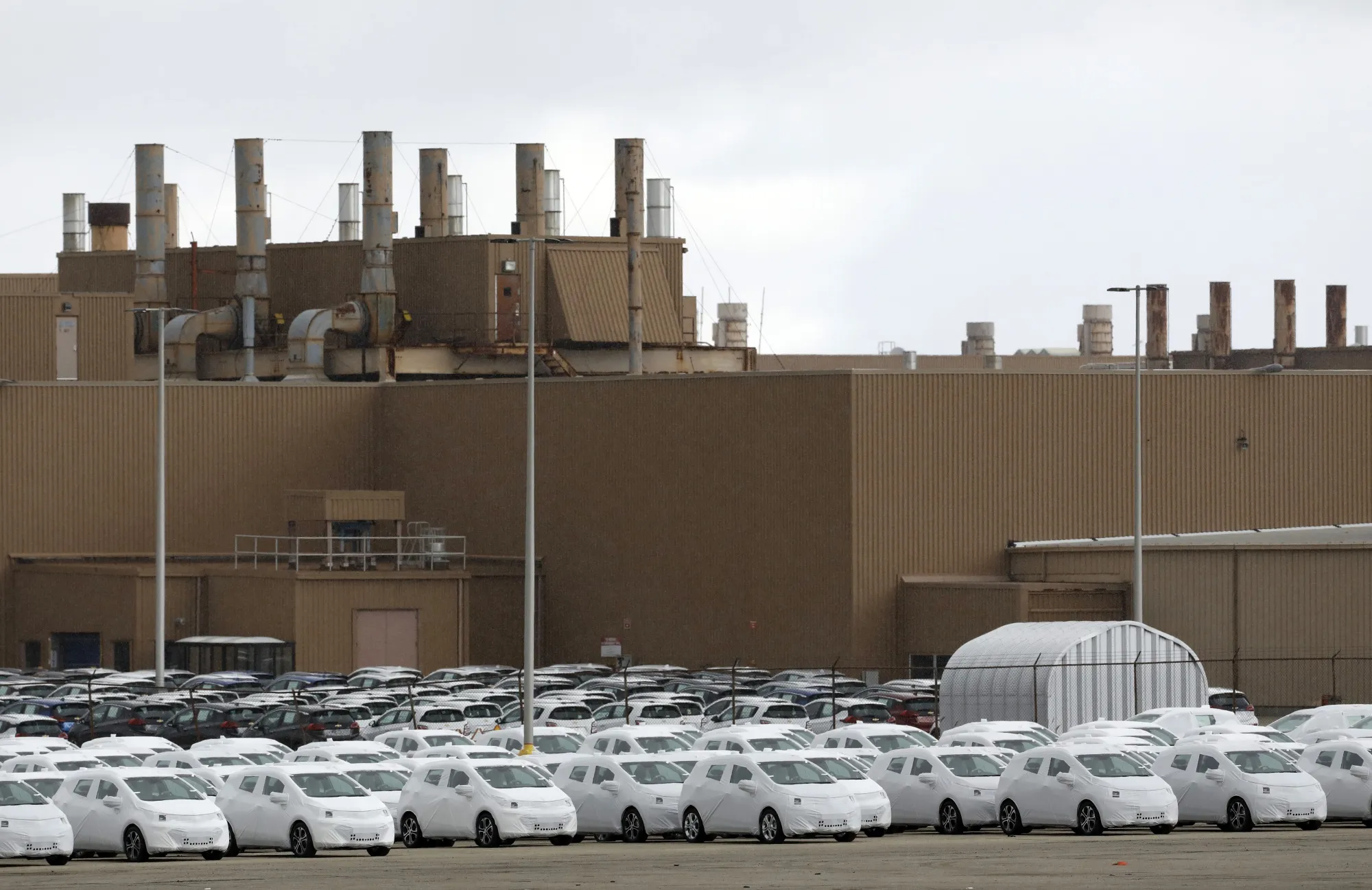 Vehicles packaged for shipment sit outside the General Motors Co. Orion Assembly plant in Orion Township, Michigan.