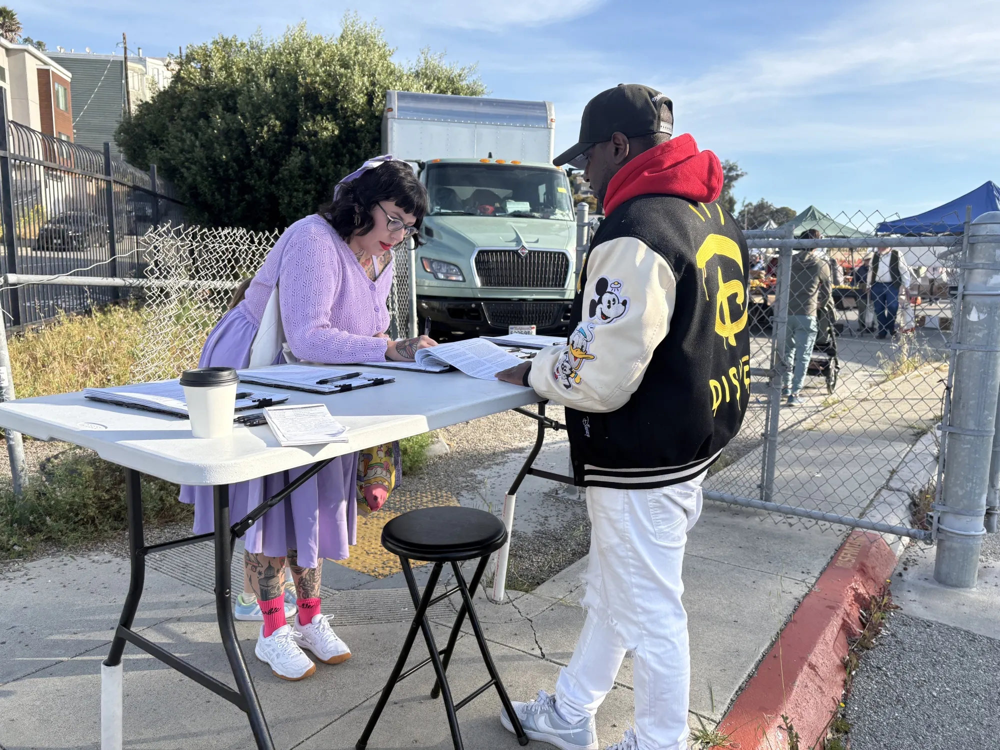 California resident Bunny McFadden signs a ballot-initiative petition at San Francisco's Alemany Farmers&nbsp;Market as Michael Pugh, a signature gatherer, looks on.