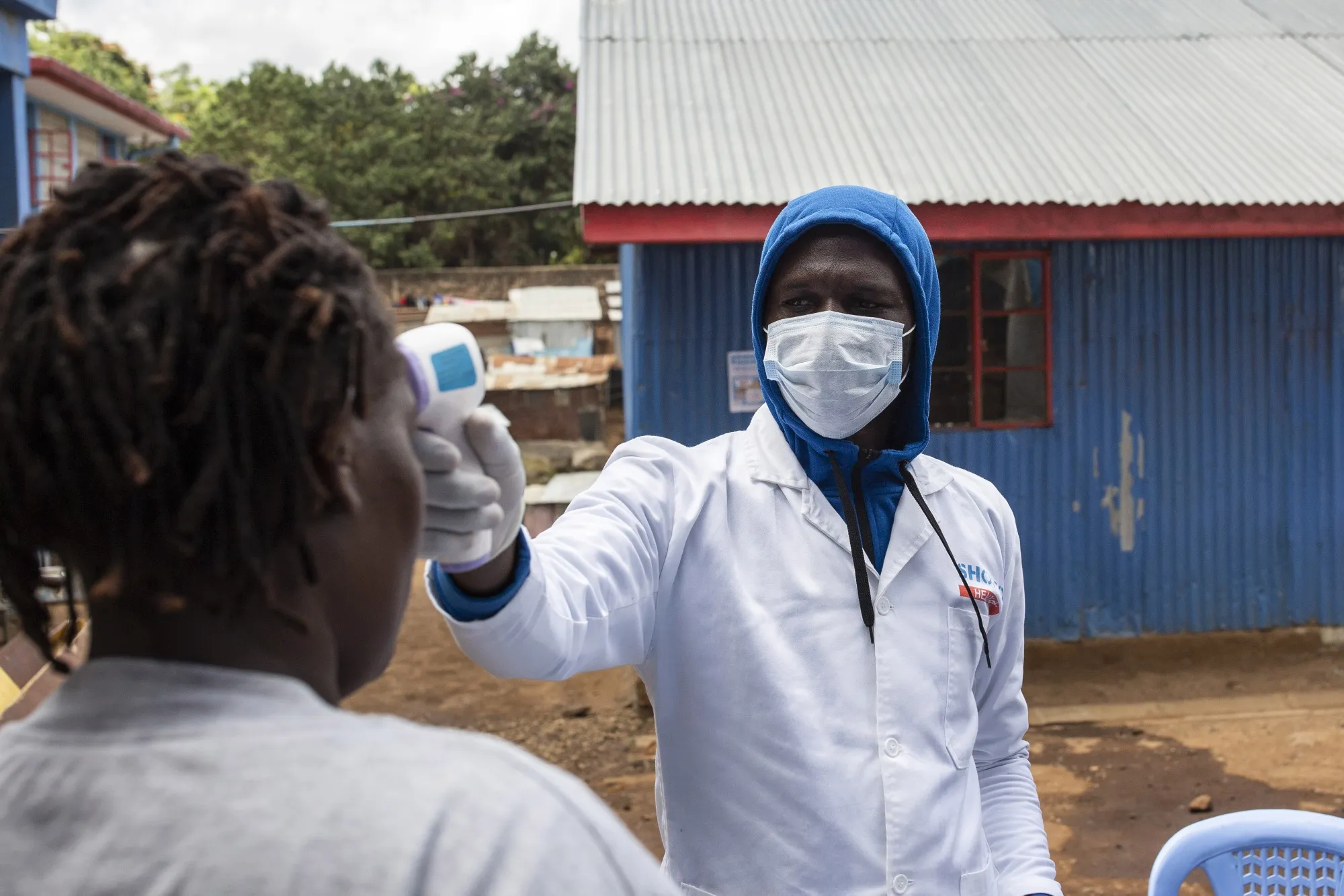 A worker performs a temperature scan on a resident at a temporary hand-washing station set up by Shining Hope for Communities (SHOFCO) in the Kibera informal settlement in Nairobi, Kenya.