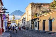 Antigua, Guatemala - April 14, 2019: Street with Santa Catalina Arch, ruins & Agua volcano behind in colonial town & UNESCO World Heritage Site.