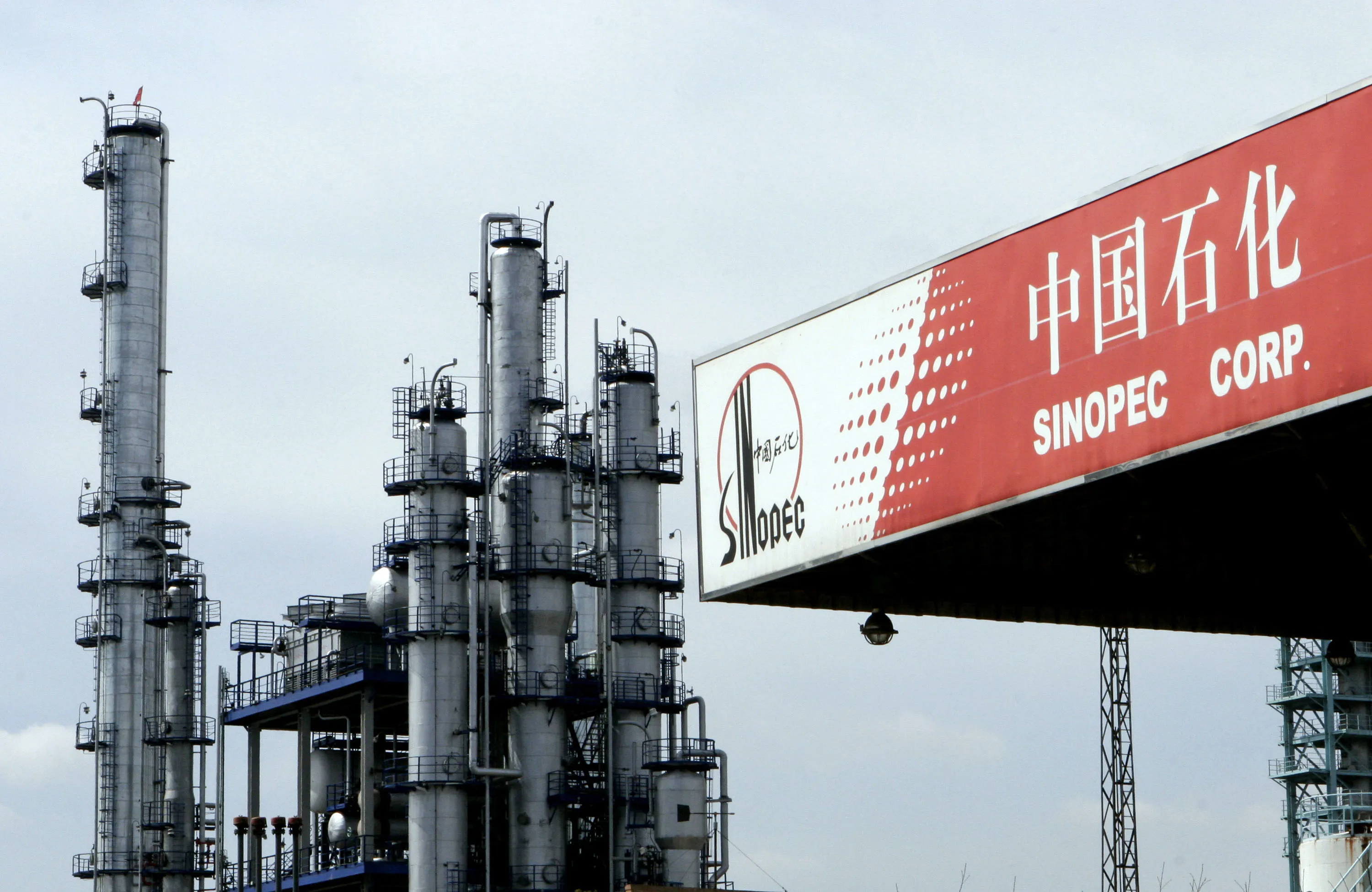 A Sinopec gas station stands in front of a Sinopec oil refinery in Pudong district, Shanghai, China.