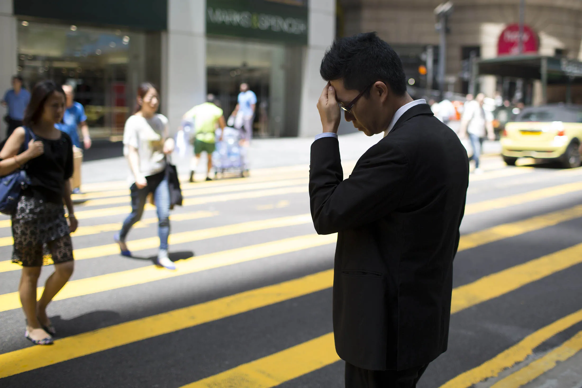 A man in a suit stands at a street crossing in the business district of Central in Hong Kong. Hong Kong dollar forwards sank to their weakest level this century.
