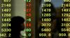 A pedestrian is reflected in an electronic stock board outside a securities firm in Kobe, Hyogo Prefecture, Japan.