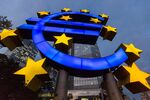 A euro-sign sculpture stands illuminated in front of European Central Bank headquarters in Frankfurt on Oct. 23, 2014.
