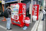 Tokyo residents purchase soft drinks from a Coca-Cola vending machine in Tokyo .