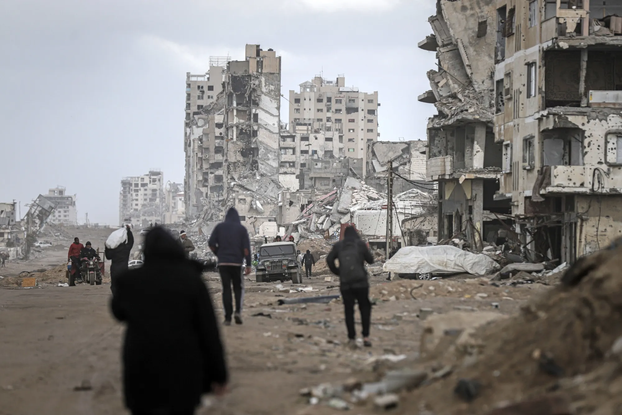 Palestinians walk past destroyed houses along a street in Gaza City, on Feb. 7.