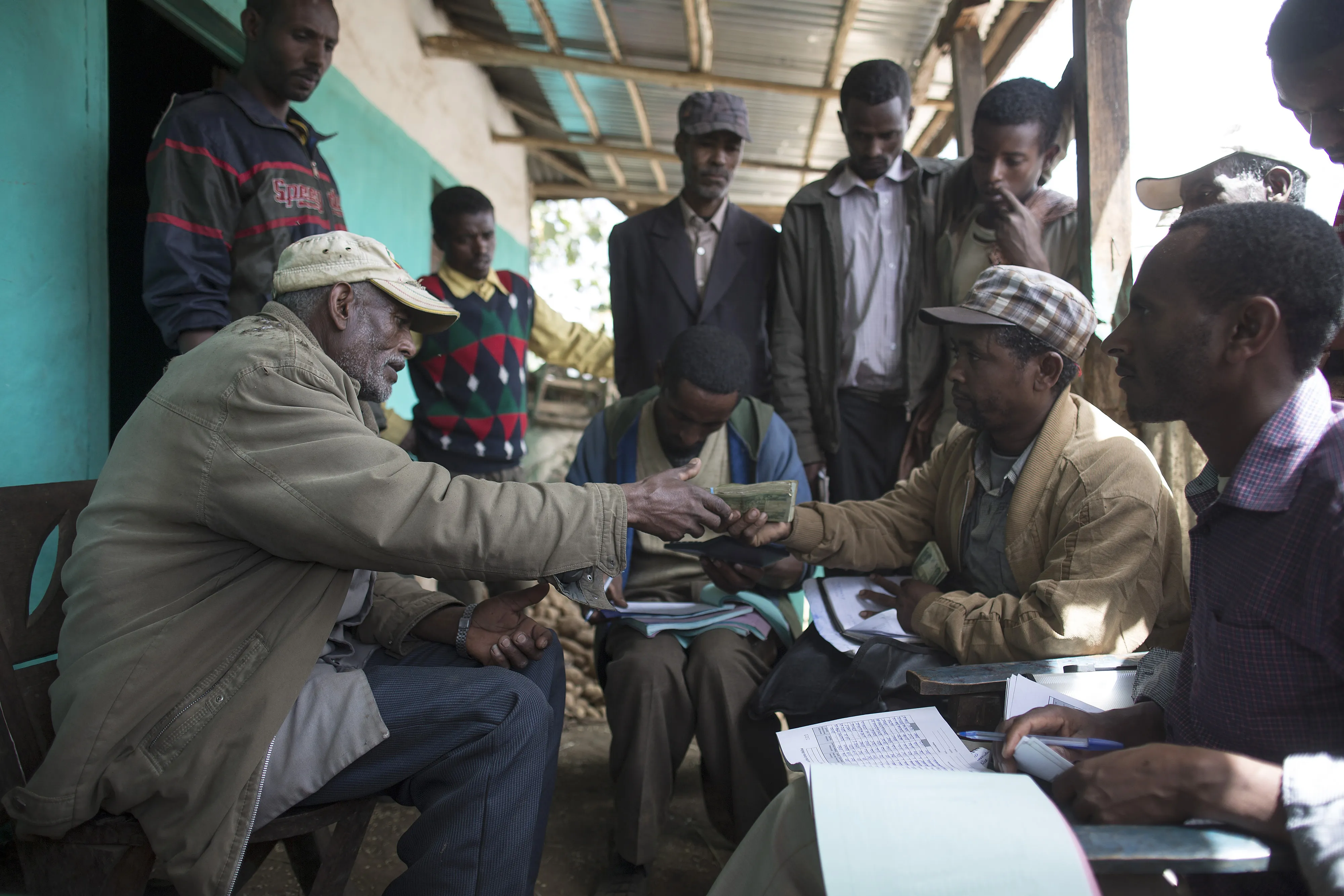 A farmer, left, accepts cash payment for his grain from a buyer in the village of Damo Dulele, Ethiopia, in February 2015. Growth in Ethiopia has beaten every other sub-Saharan country over the past decade.
