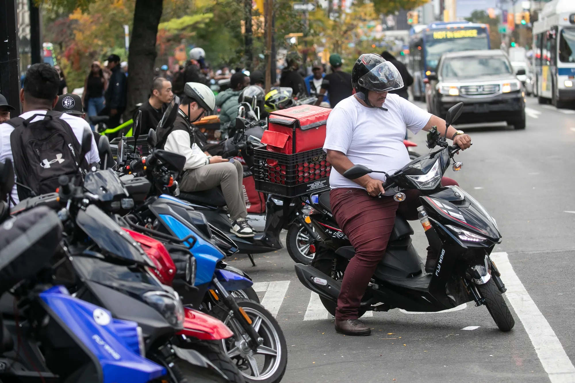Delivery workers wait for orders at a Chick-fil-A restaurant in Brooklyn, New York. A new minimum wage mandate has prompted Uber and DoorDash to make changes to their platforms to balance the increased costs.