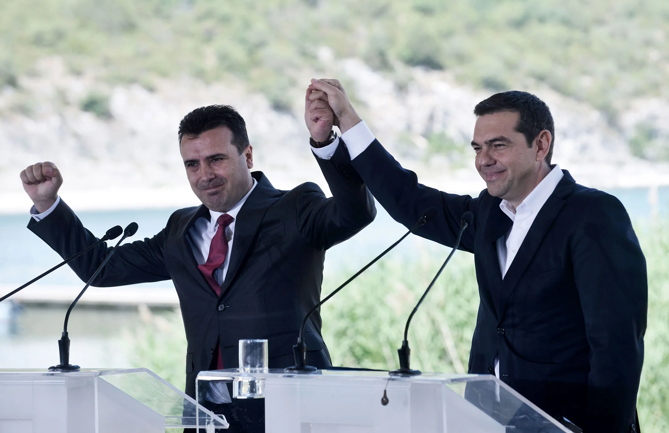 Greek Prime Minister Alexis Tsipras and Zoran Zaev raise their hands during a signing ceremony between officials from Greece and Macedonia at Prespes Lake on June 17.&nbsp;