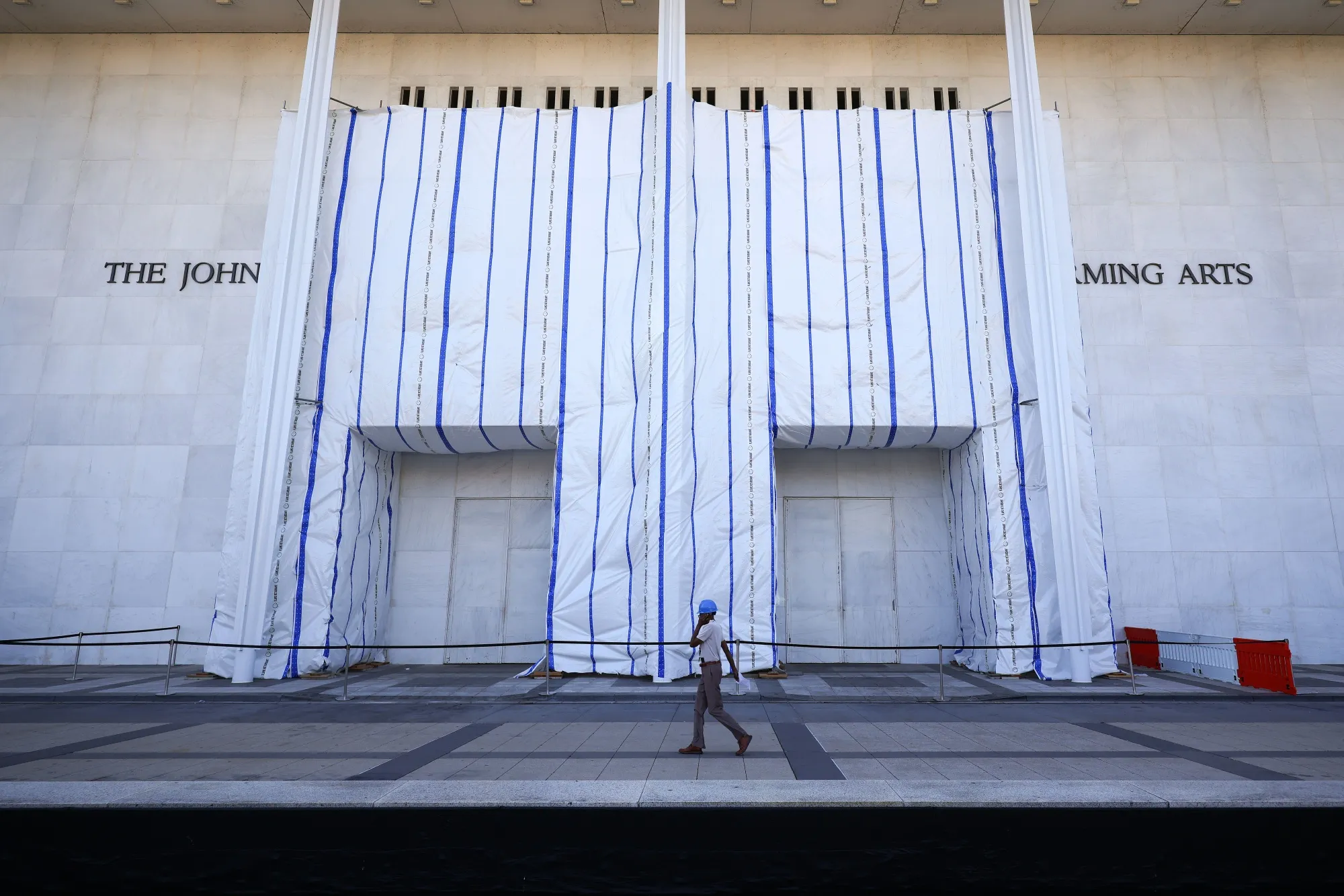 Workers walk past a recently closed John F. Kennedy Memorial Center for the Performing Arts in Washington on Sept. 16.