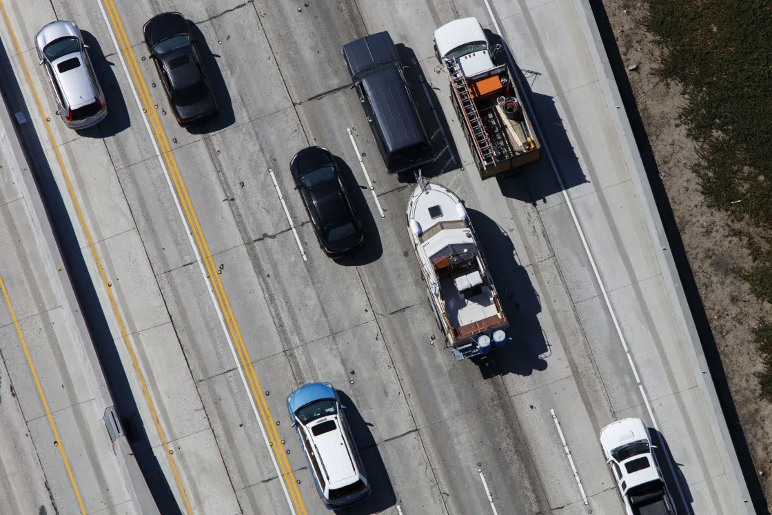 A sports utility vehicle (SUV) tows a boat as rush hour traffic moves slowly on the 405 Freeway in this aerial photograph taken over the Westwood neighborhood of Los Angeles, California, U.S., on Friday, July 10, 2015. The greater Los Angeles region routinely tops the list for annual traffic statistics of metropolitan areas for such measures as total congestion delays and congestion delays per peak-period traveler.