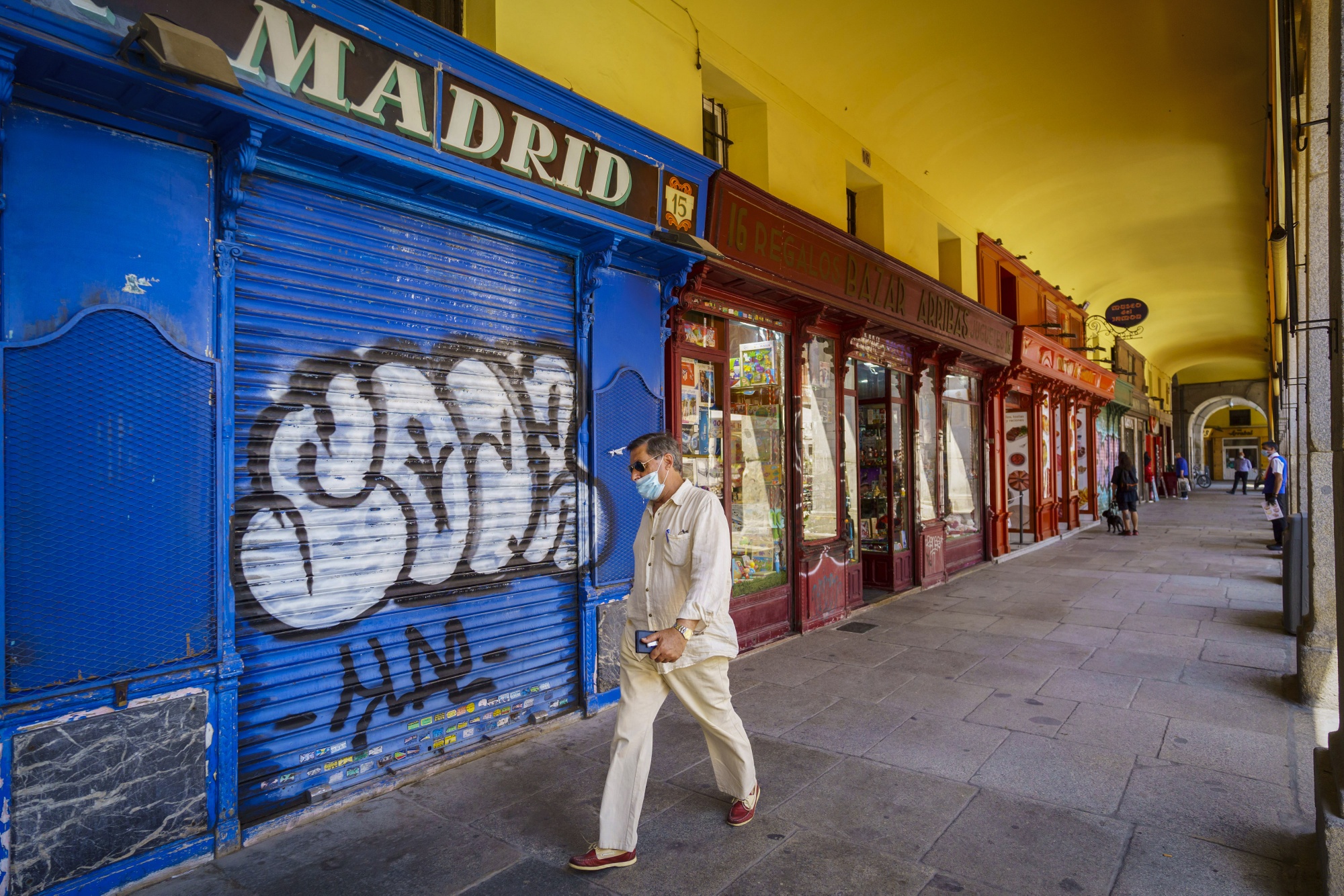 A pedestrian passes a shuttered business in Madrid, Spain.