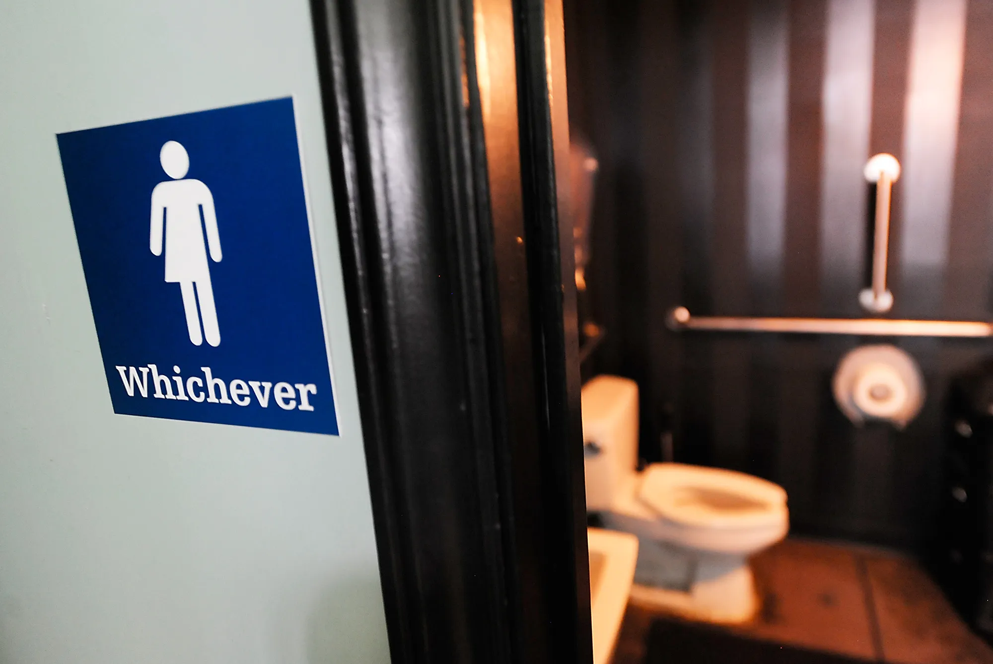 A gender neutral sign is posted outside a bathroom.