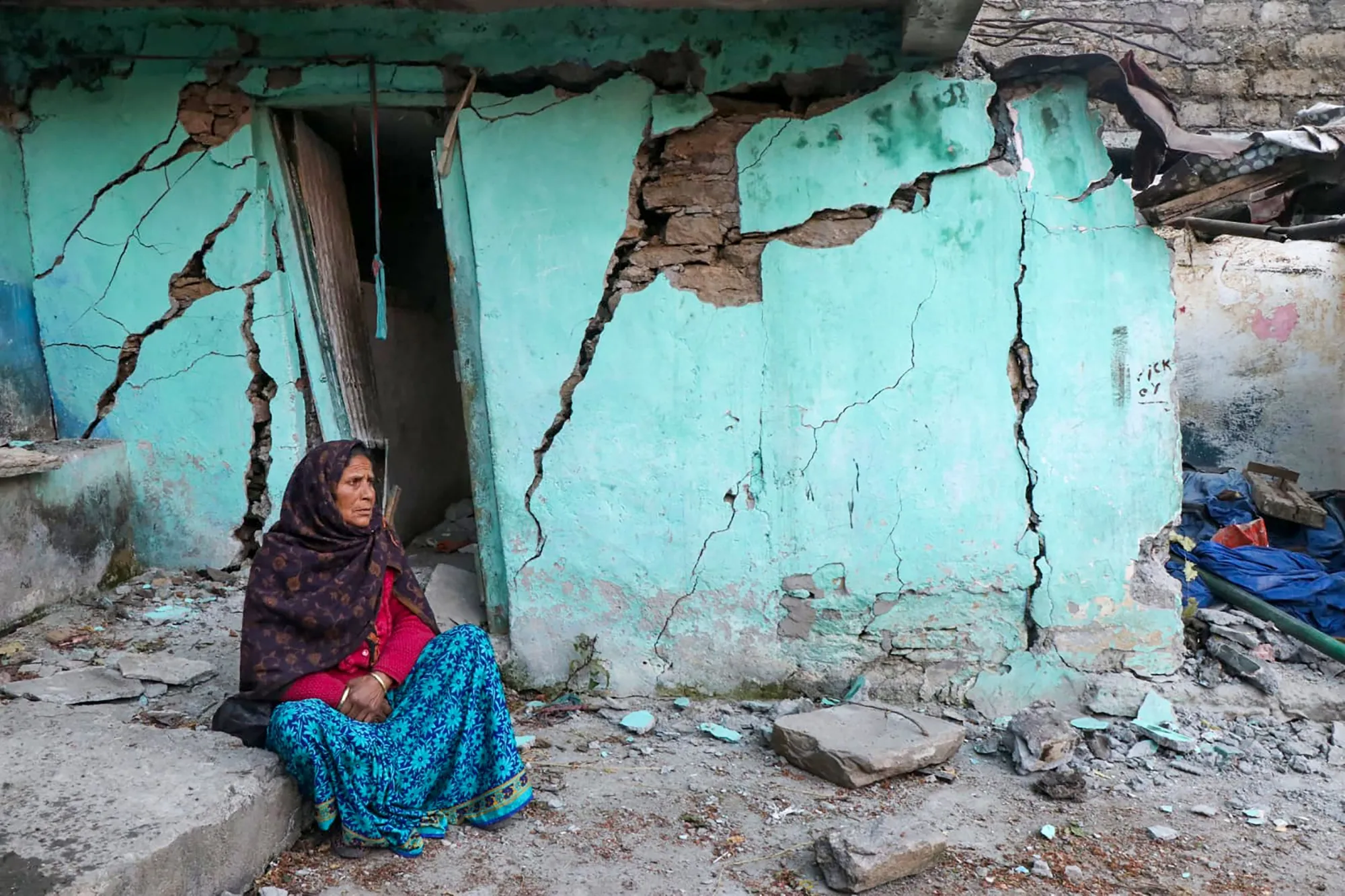A woman sits beside a cracked wall of her house at Joshimath on Jan. 10.&nbsp;