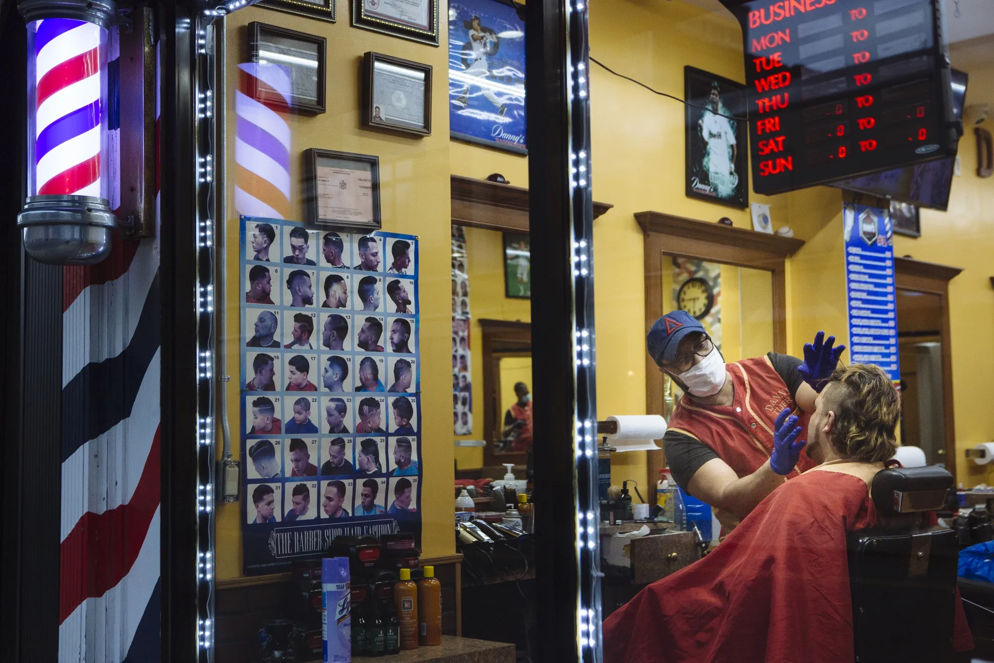 A barber wears a protective mask and gloves while cutting a customer's hair at a shop in New York, on&nbsp;March 16.