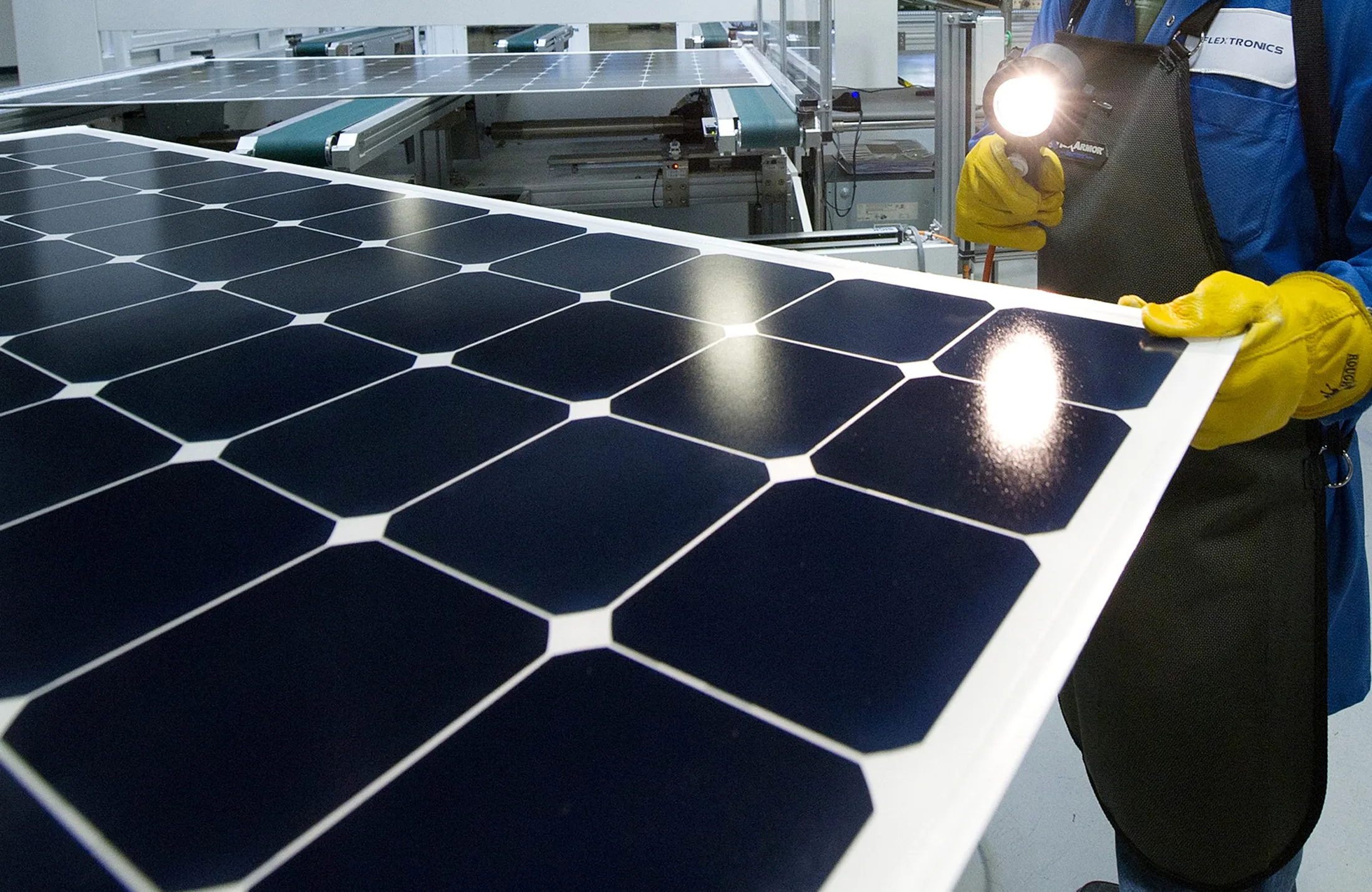 An employee of SunPower Corp. trims the edges and checks solar panels at the SunPower Corp. module manufacturing plant at Flextronics in Milpitas, California.