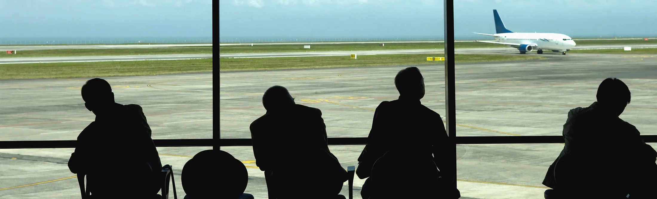 Businessmen watching airplanes on the&nbsp;tarmac.

