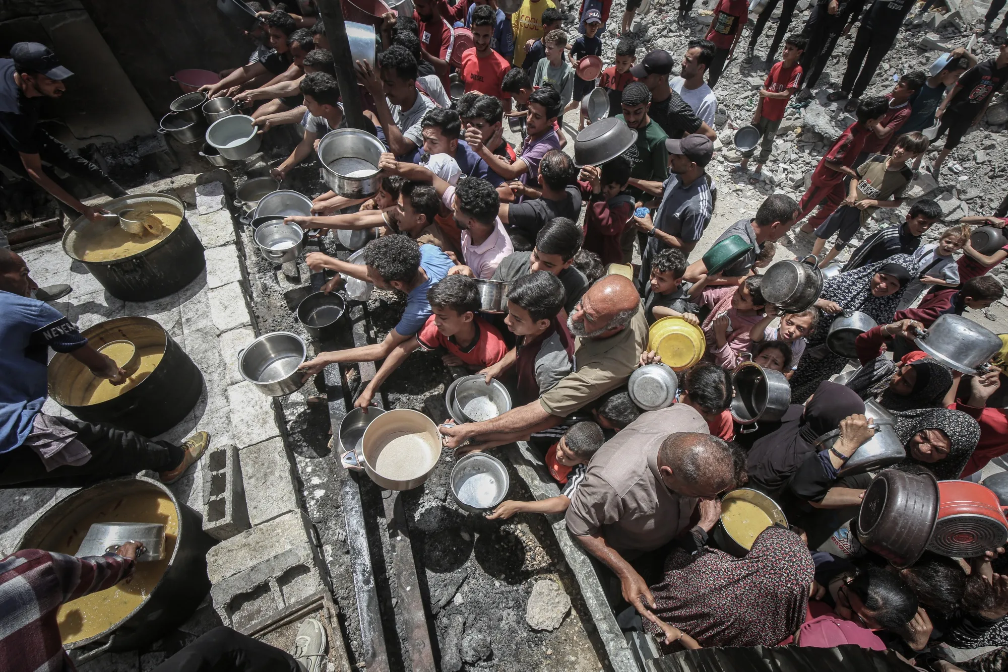 Displaced Palestinians collect cooked food from a community food kitchen in Jabaliya, northern Gaza, on May 19.