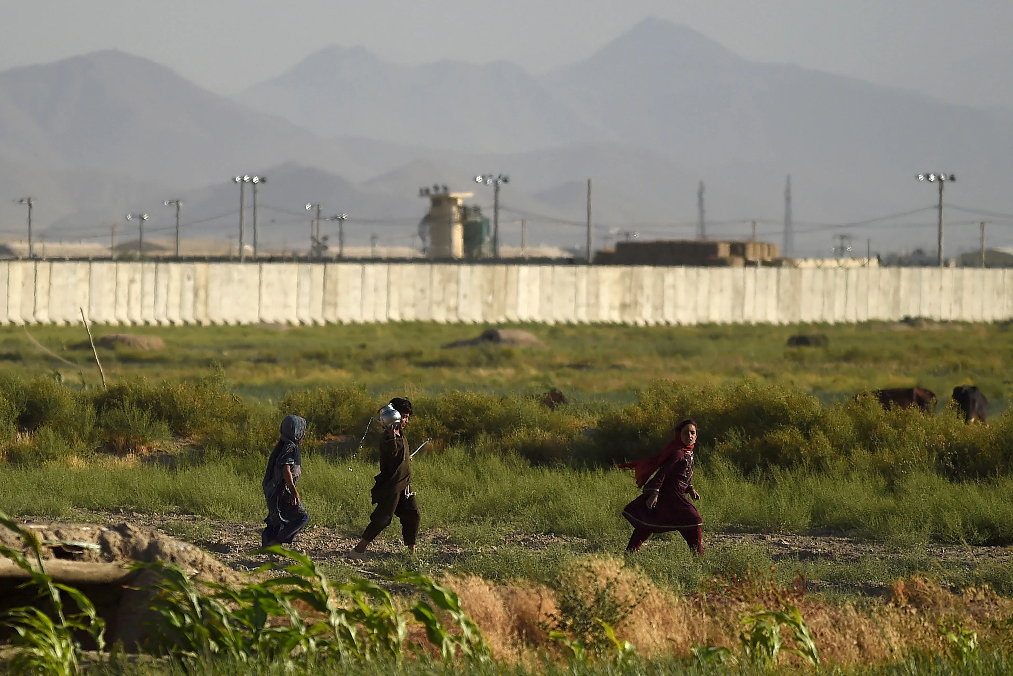 Children walk along a path outside a US military base in Bagram.