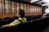 Men look at an electronic stock board at the Asia Plus Securities Pcl headquarters in Bangkok, Thailand, on Monday, Feb. 3, 2014. Thailand’s baht rose the most in three weeks and stocks gained after voters defied protesters’ efforts to disrupt polls and cast ballots across 90 percent of the country yesterday without triggering major violence.