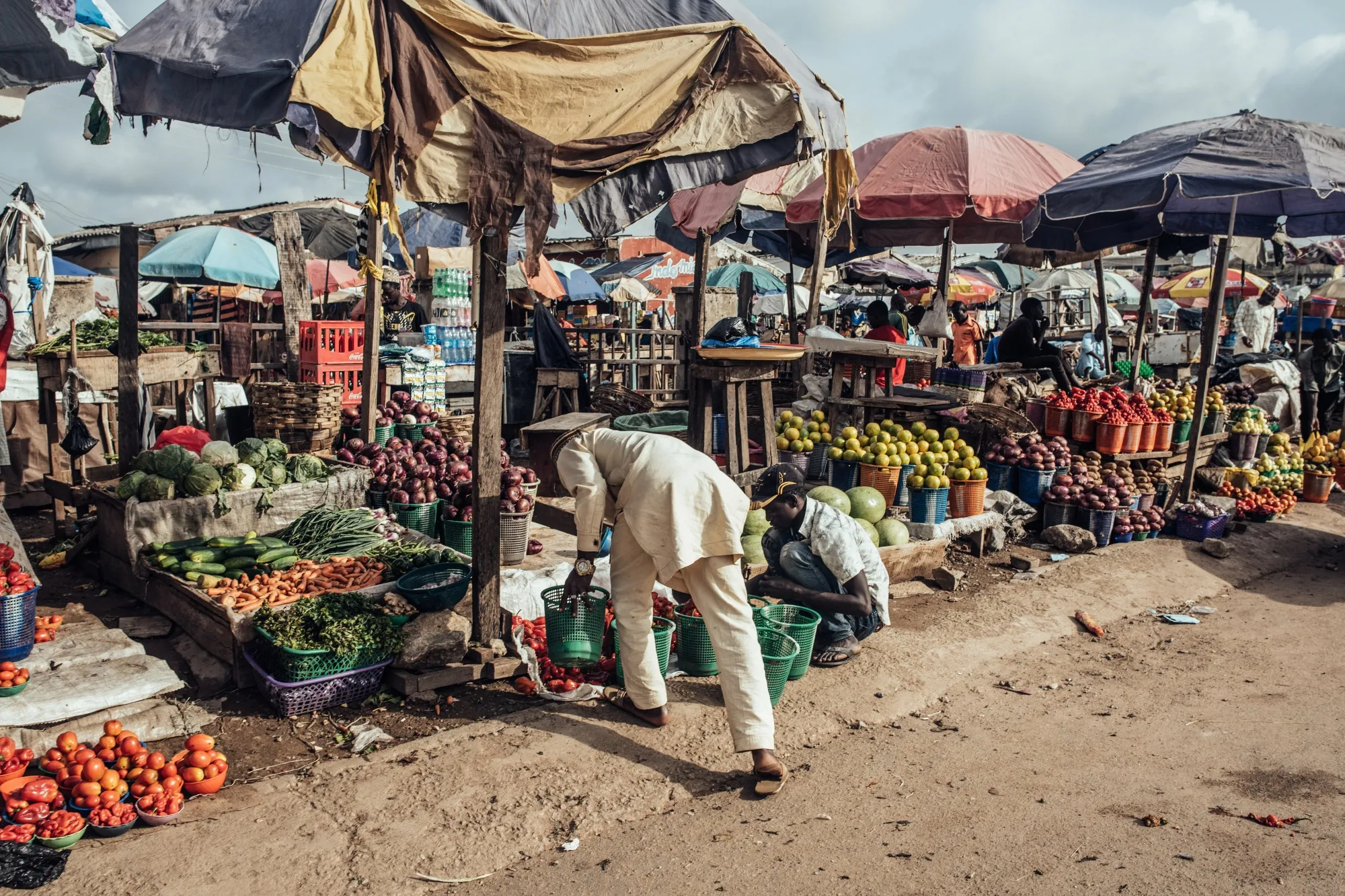 A vendor arranges vegetables on a stall at a market.