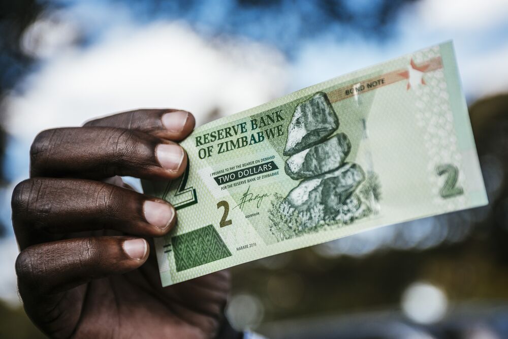 A man holds a Zimbabwean two dollar bond banknote for an arranged photograph in Harare, Zimbabwe.