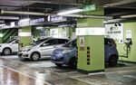 Electric automobiles sit connected to a charging station in Beijing,