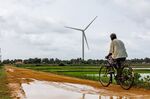 A wind turbine and a local resident on a bicycle in Jaffna district, Sri Lanka.