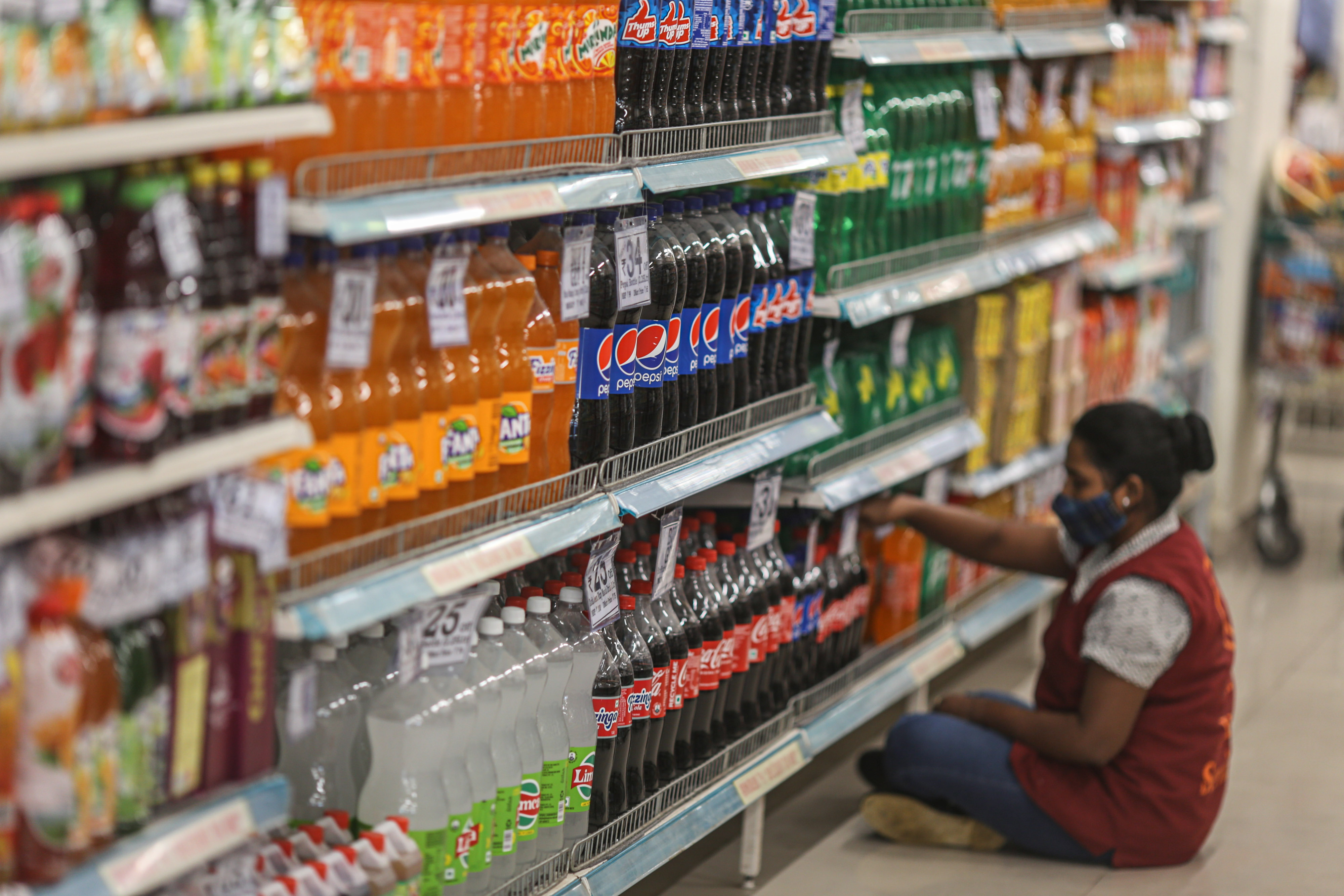 An employee arranges shelves at a supermarket in Mumbai.