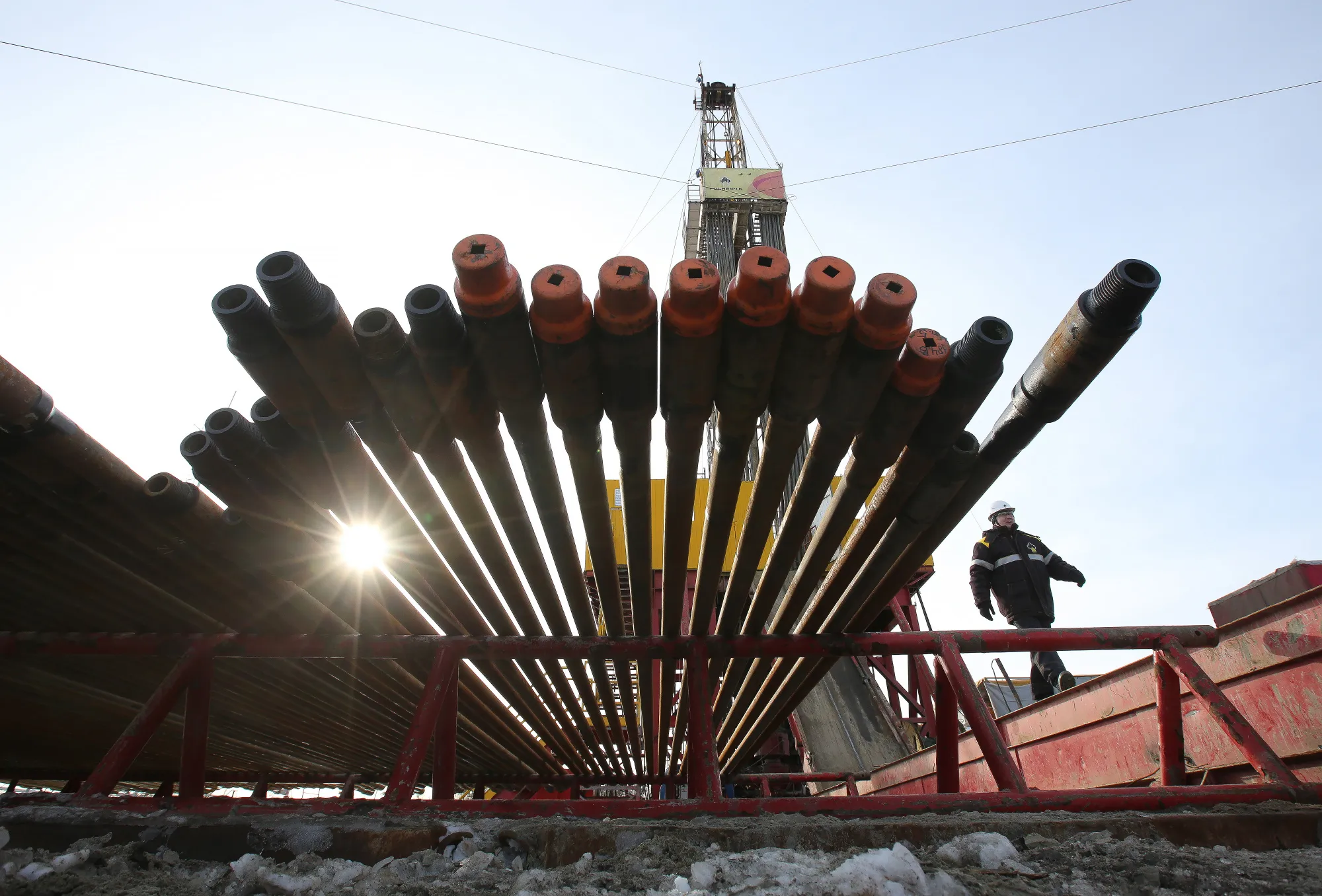 A worker passes an oil drilling rig and drill pipes in the Samotlor oilfield near Nizhnevartovsk.
