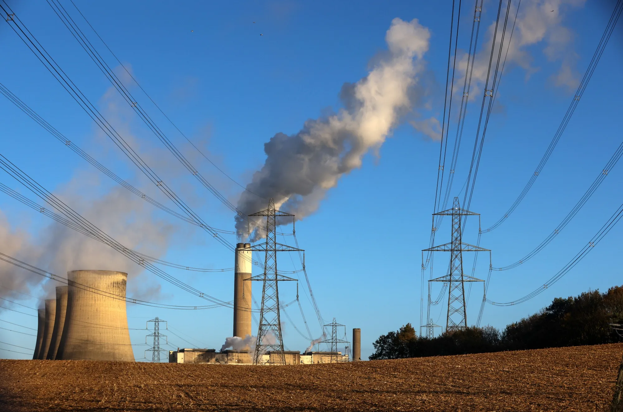 Electricity transmission pylons against a backdrop of cooling towers at a power station in Ratcliffe-on-Soar, U.K.