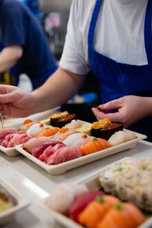 A chef at Oroshi Fish Co. places sushi in a to go box.