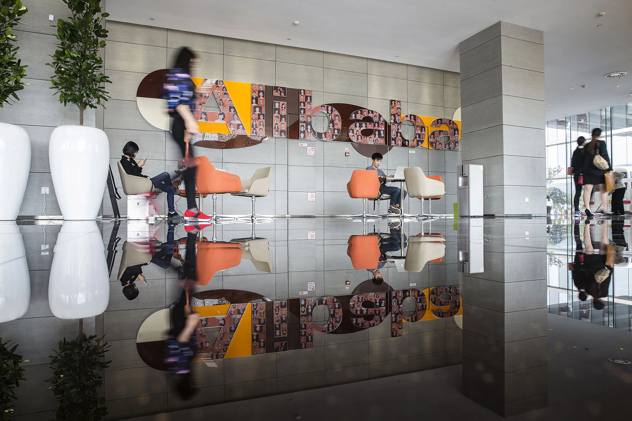 Employees and visitors sit in a building lobby at the Alibaba Group Holding Ltd. headquarters in Hangzhou, China.