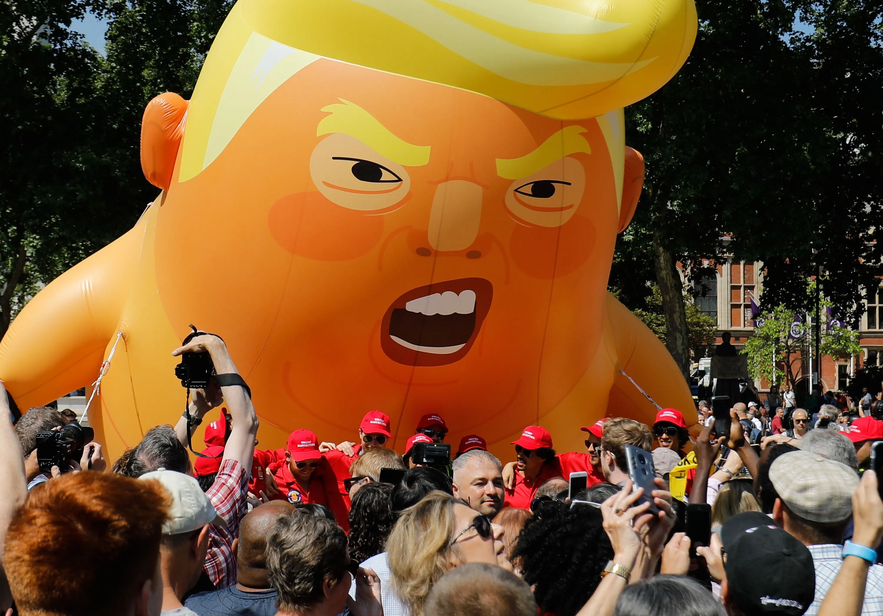 Activists inflate a giant balloon depicting Donald Trump as an orange baby during a demonstration against Trump's visit to the UK in Parliament Square in London on July 13, 2018.