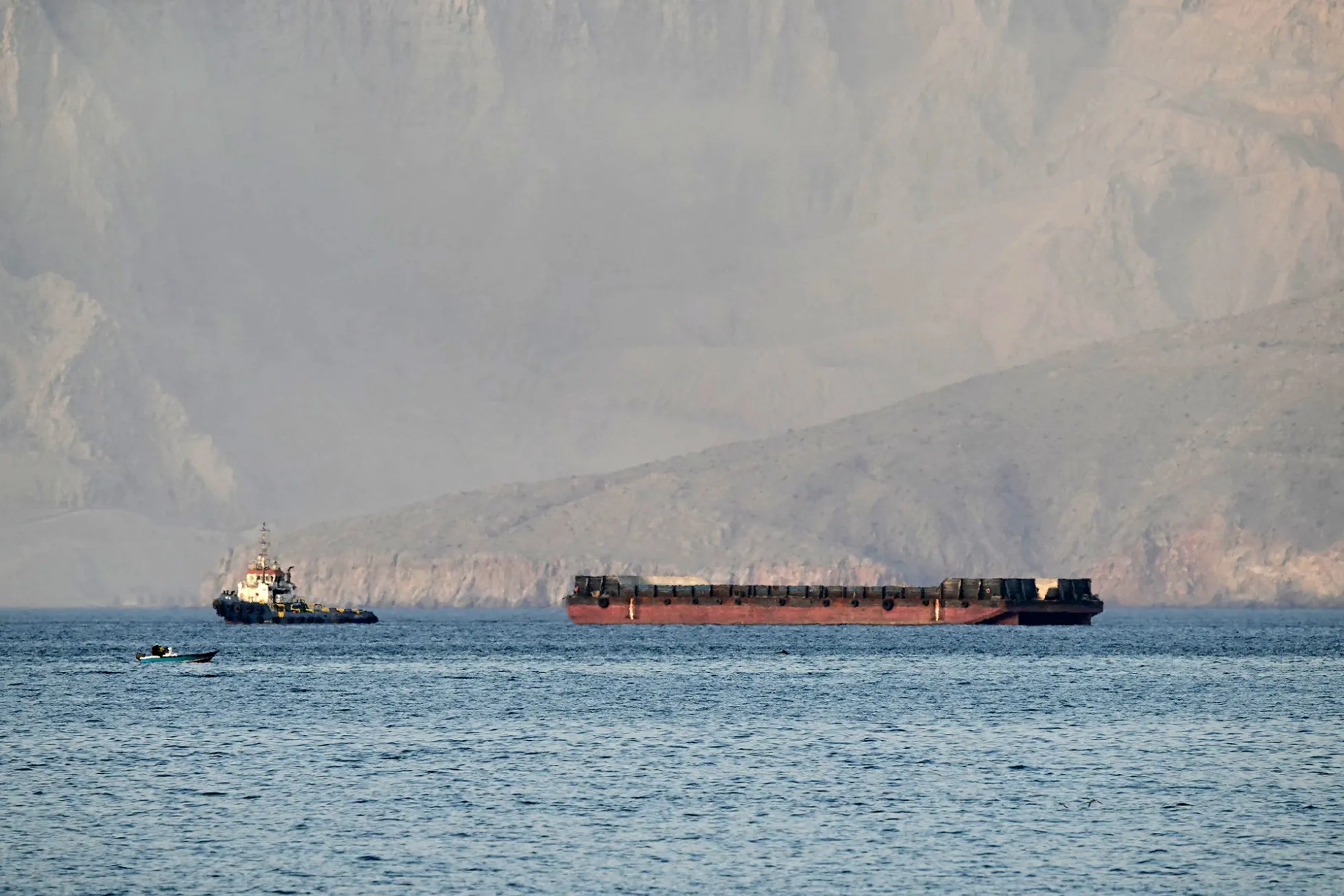 A tug boat tows a ship&nbsp;off the&nbsp;northern Oman's Musandam Peninsula, overlooking the Strait of Hormuz on June 24.