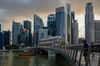 People cross the Jubilee Bridge in the Marina Bay area of Singapore with the central business district skyline in the background.