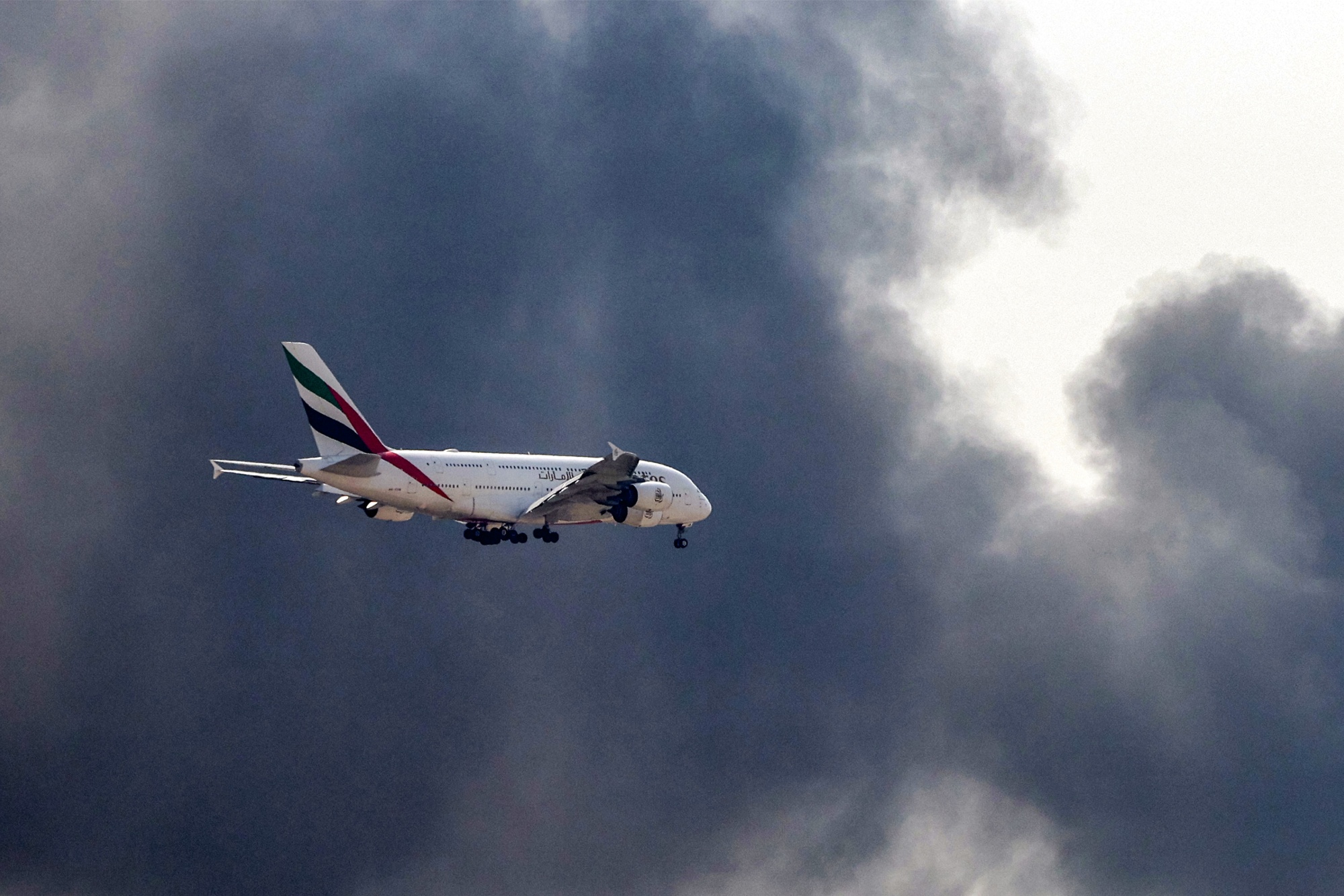 An Emirates Airbus A380 passes smoke from an ongoing fire as it prepares to land at Dubai Airport, on March 16. Source: AFP/Getty Images