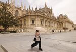 A visitor walks across an empty square beside Seville cathedral.