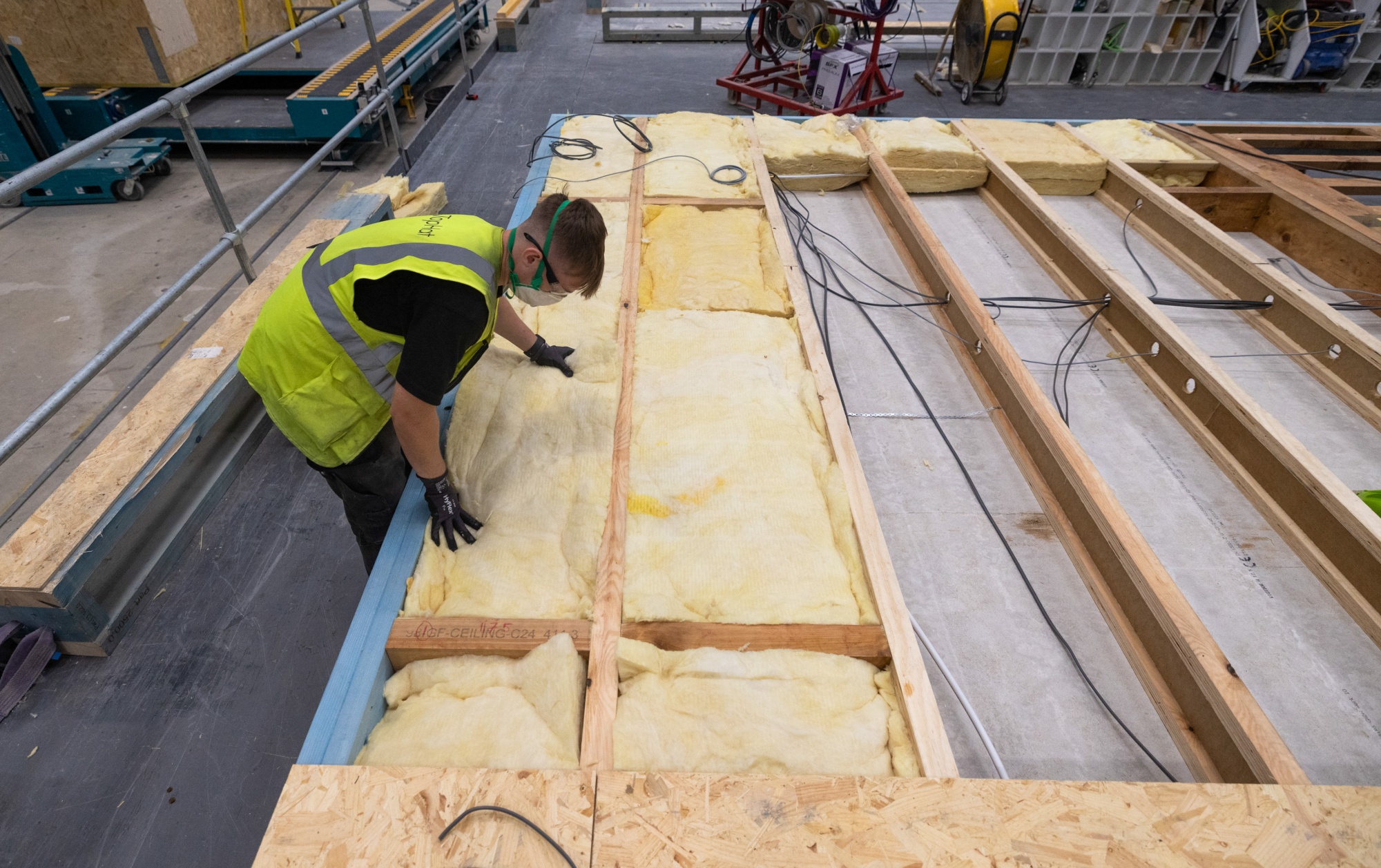 An employee places insulation material in to the roof section of a modular house.