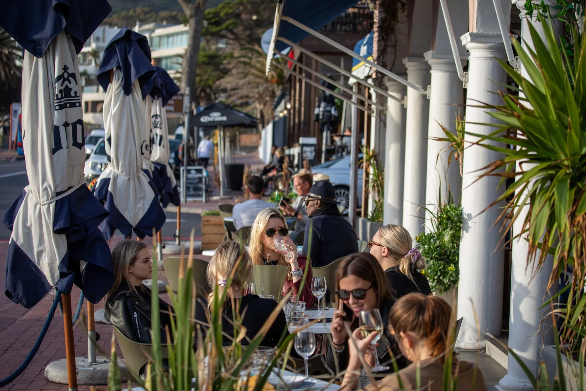 Customers sit at tables outside on the terrace area of a cafe in the Camps Bay area of Cape Town, South Africa on Aug. 19.