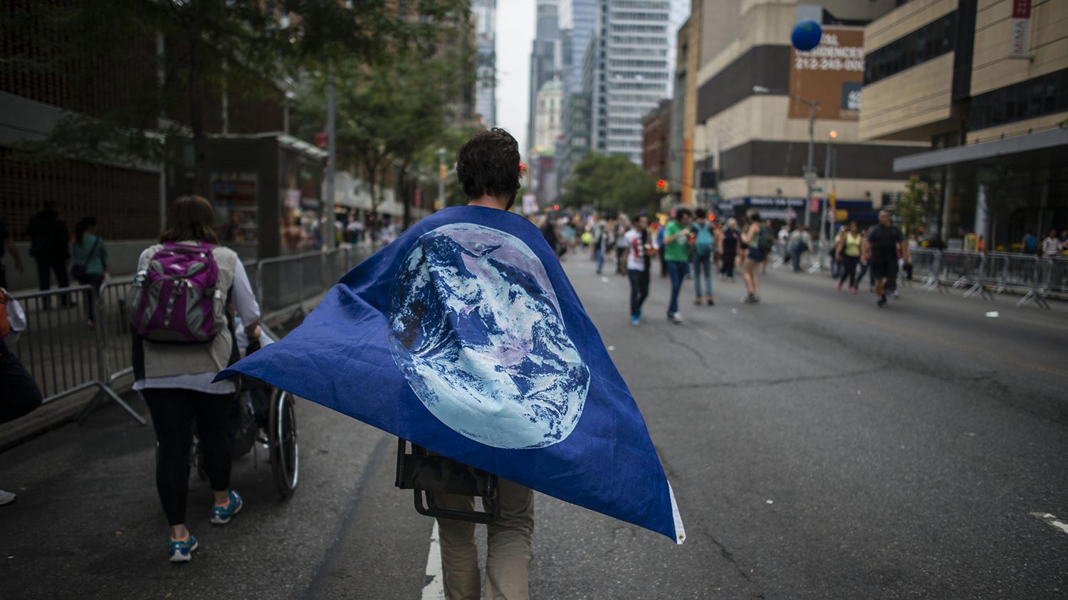 A demonstrator wears a flag as a cape during the People's Climate March in New York, U.S., on Sunday, Sept. 21, 2014.
