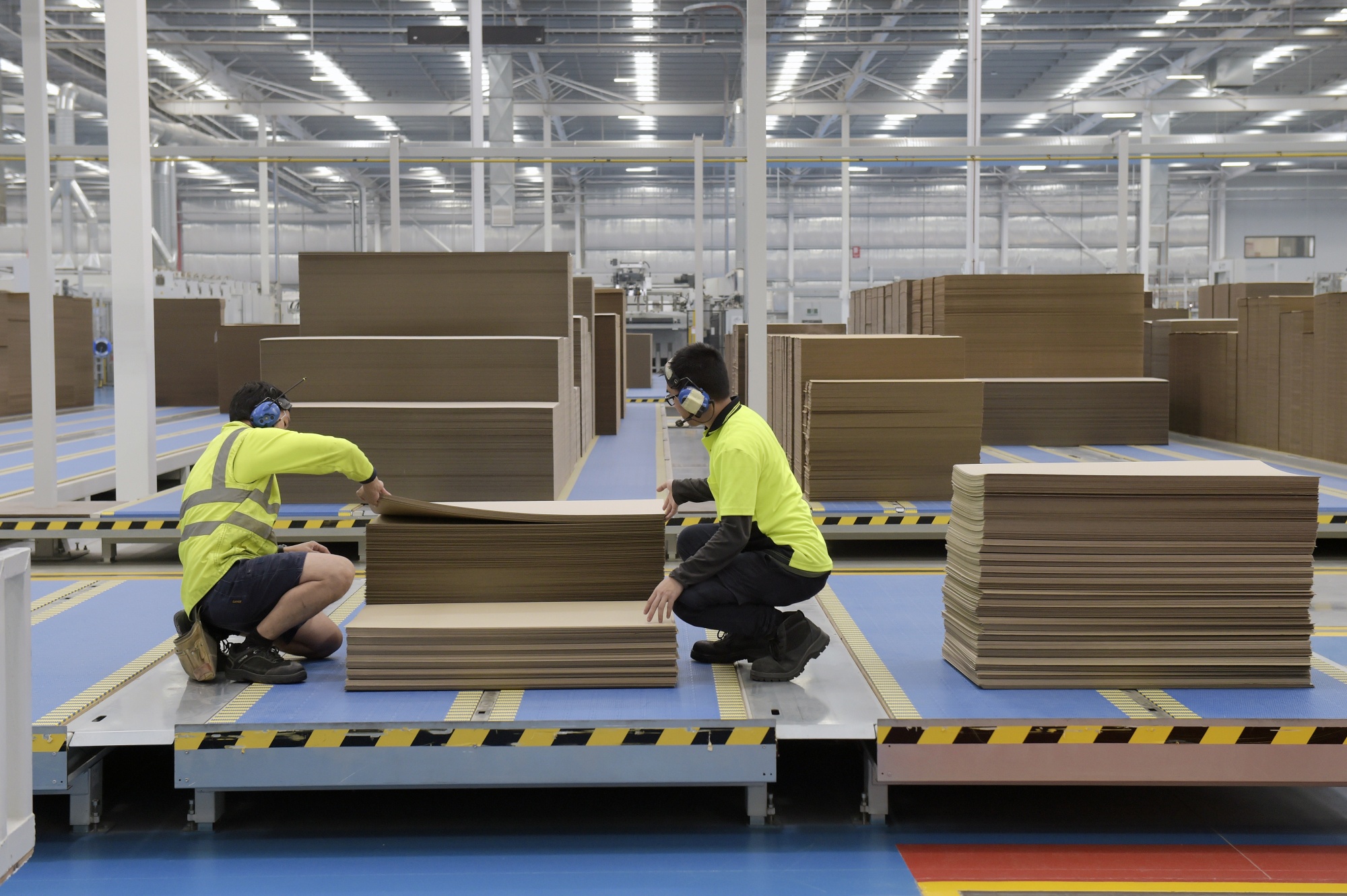 Employees check a stack of cardboard at the end of a conveyor&nbsp;in Melbourne, Australia.