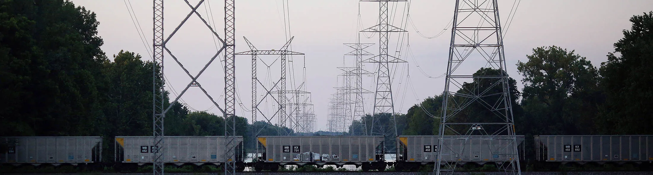 An empty coal train passes underneath power lines leading away from the Duke Energy Corp. Gibson Station power plant in Owensville, Indiana, U.S., on Thursday, July 23, 2015. Coal reclaimed its ranking as the top fuel for generating electricity at U.S. power plants in May, beating natural gas, which took the number one spot for the first time in April.
