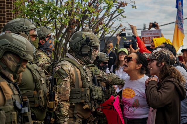 Immigration officials in military gear are confronted by protesters 