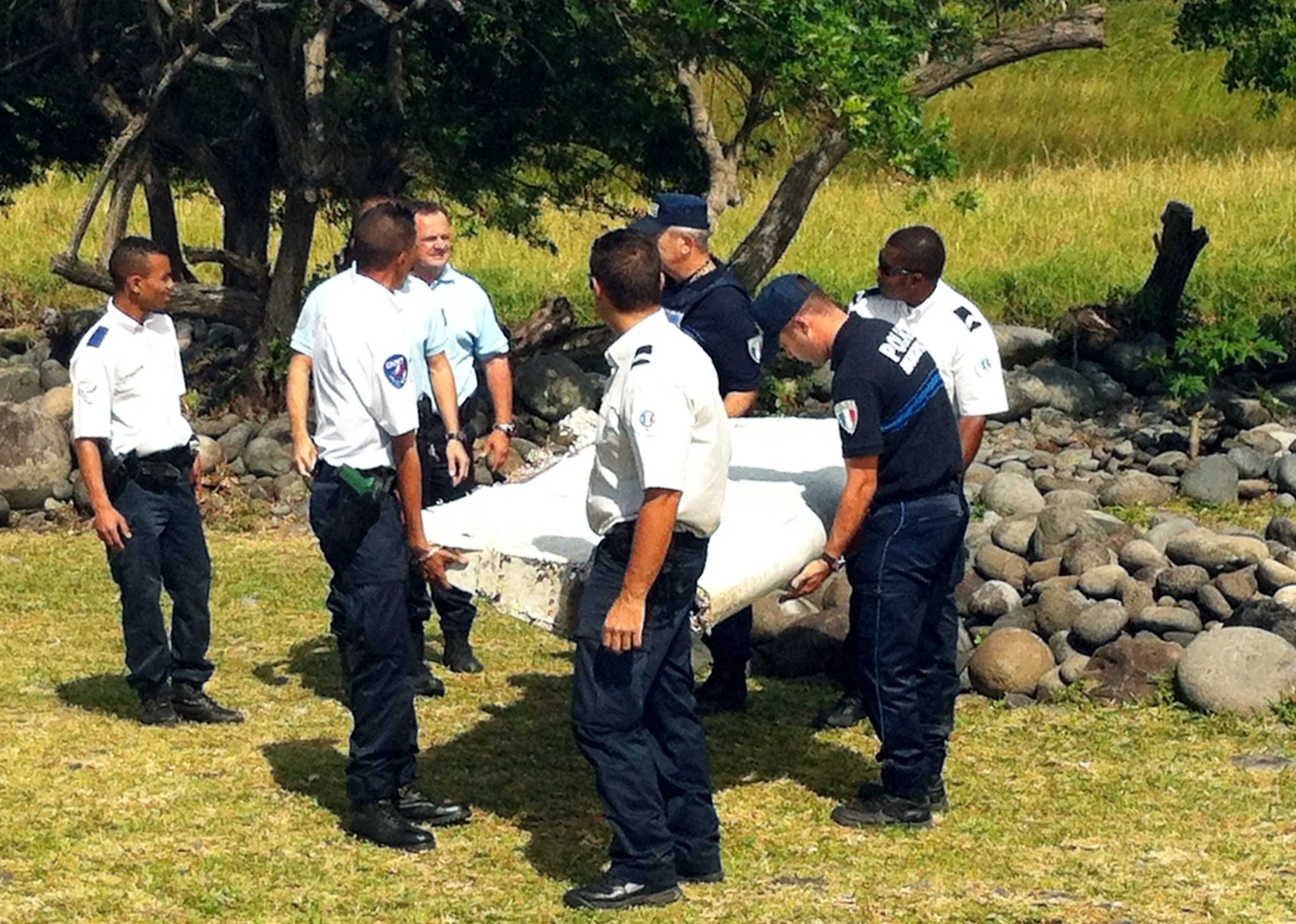 Police carry a piece of debris from an aircraft found on Reunion Island, on July 29, 2015.