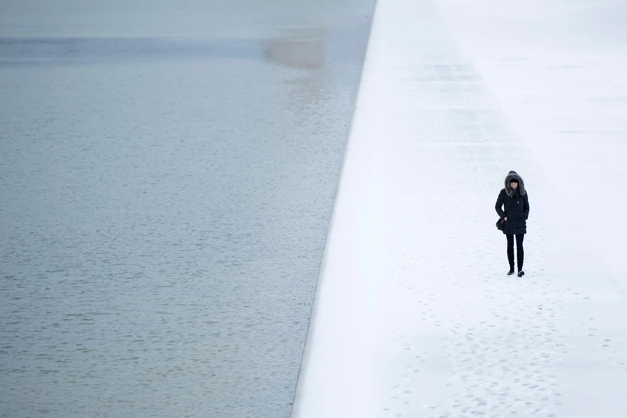 A visitor walks past the reflecting pool on the National Mall after a winter storm on March 14, 2017, in Washington, D.C.
