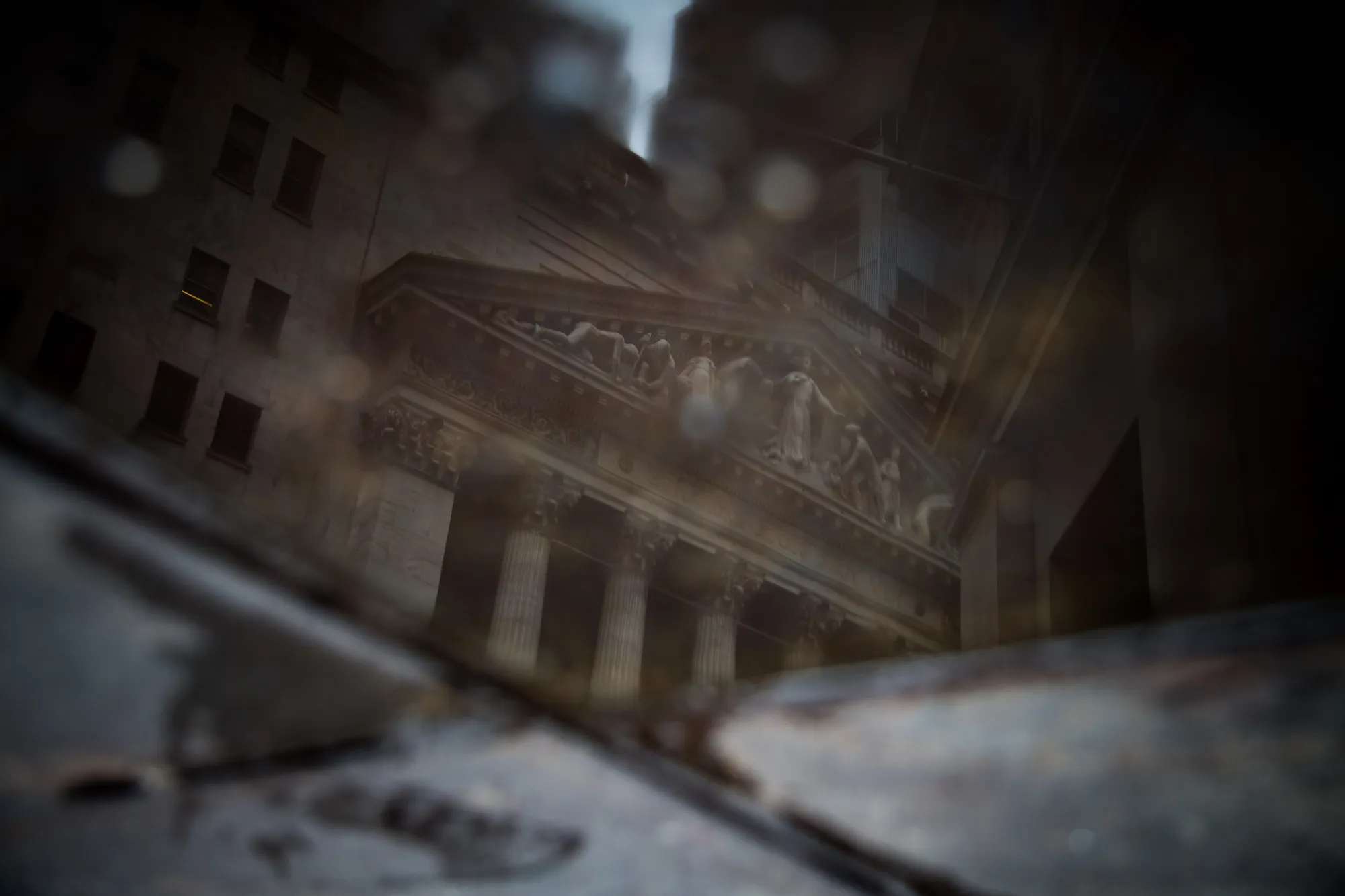 The New York Stock Exchange (NYSE) is reflected in a puddle of water on Wall Street in New York, U.S.